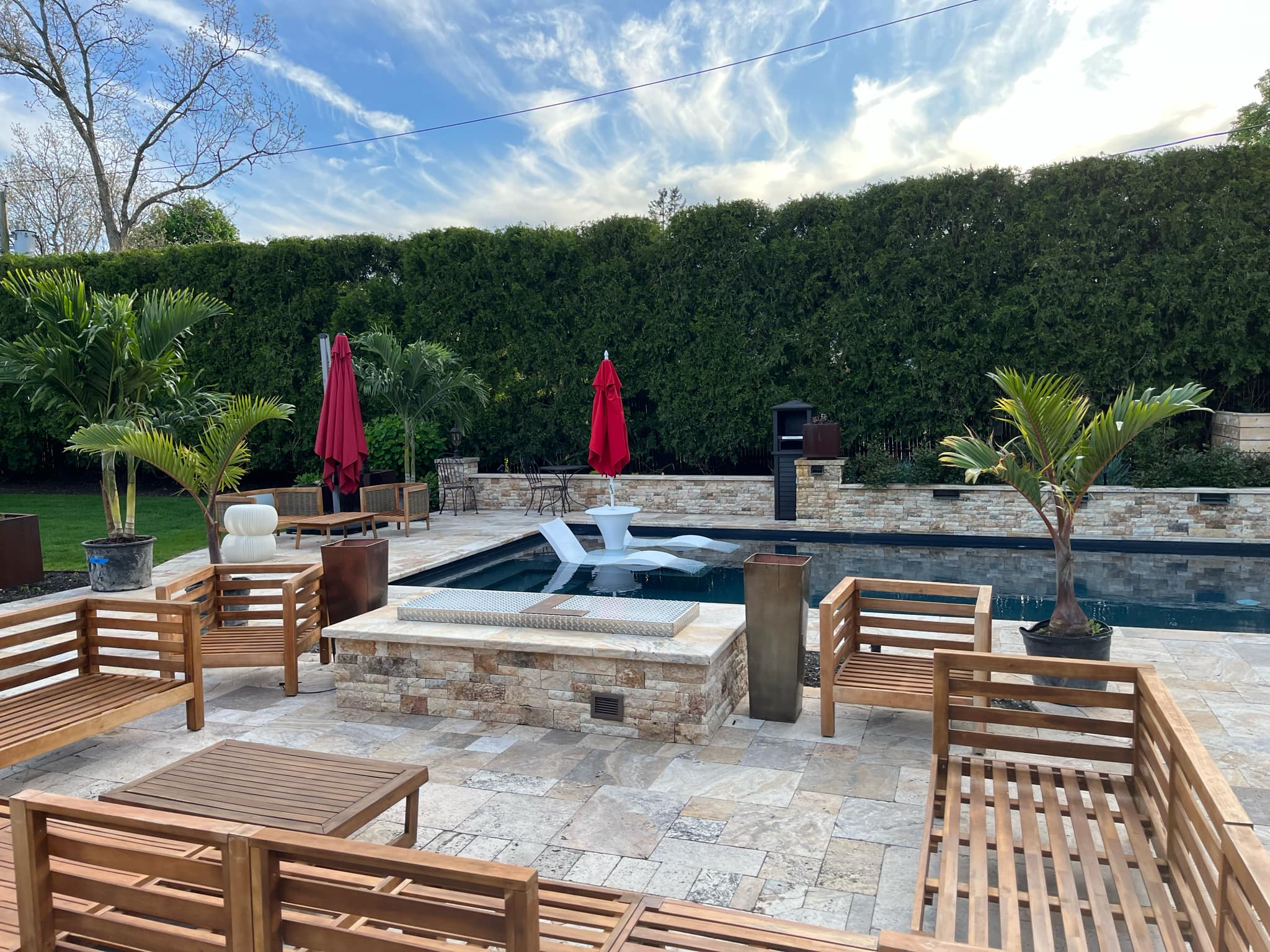 Tropical palm trees placed around a backyard pool on Long Island – Suffolk Palms delivery and setup